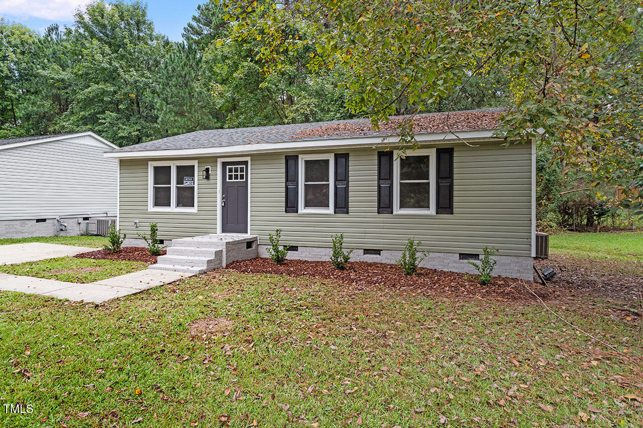 a front view of house with yard and trees in the background