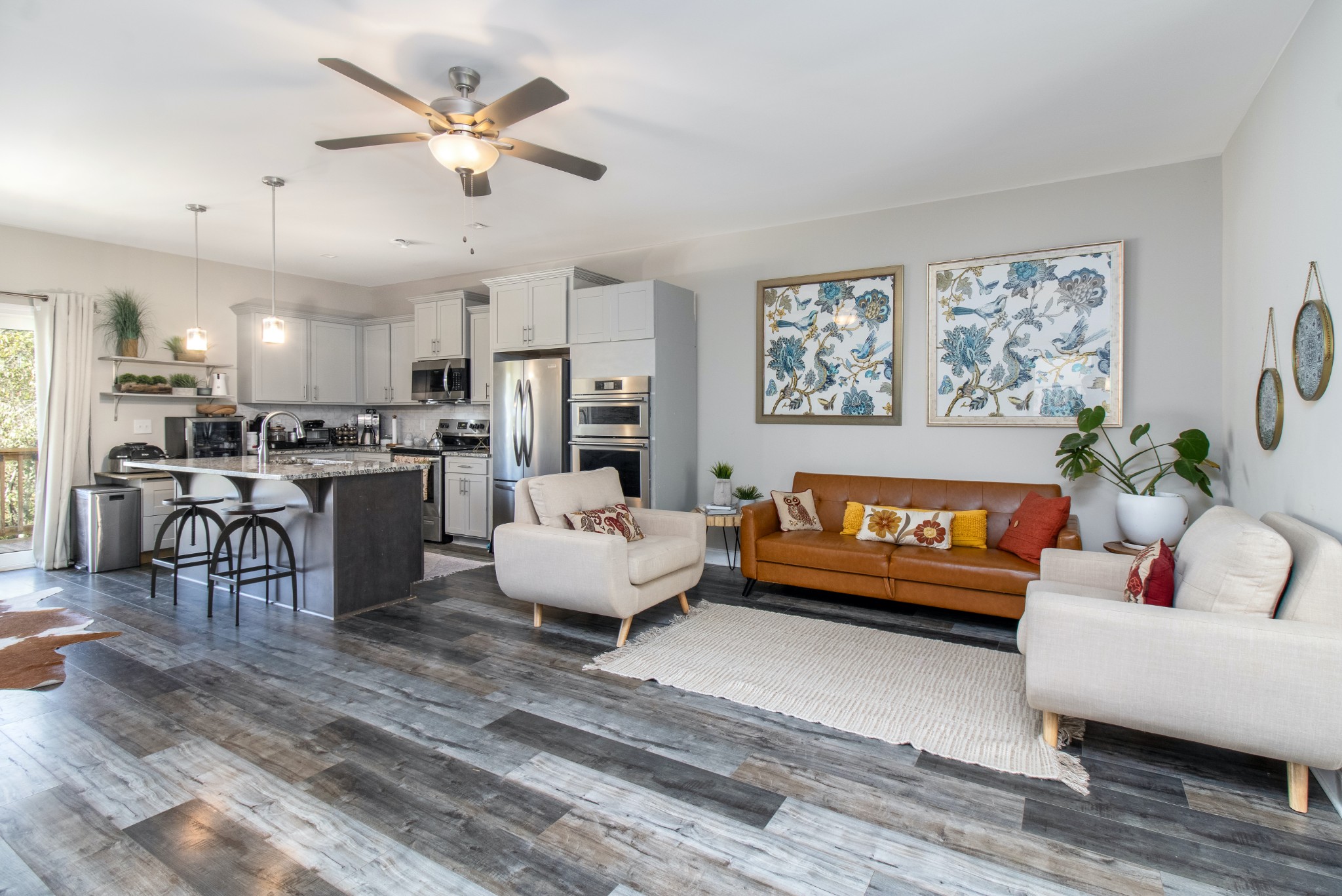 a living room with furniture kitchen area and a wooden floor