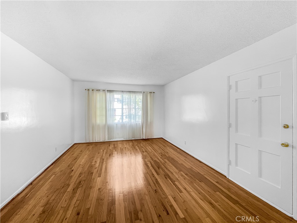 a view of an empty room with wooden floor and window