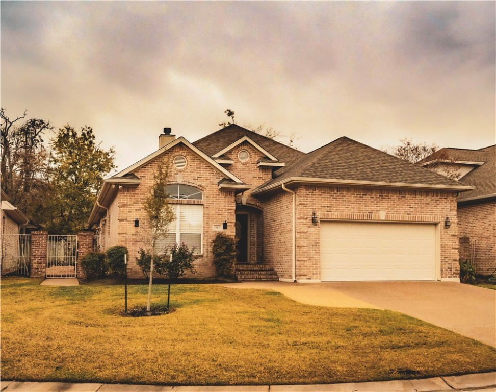 View of front of home with a garage and a yard