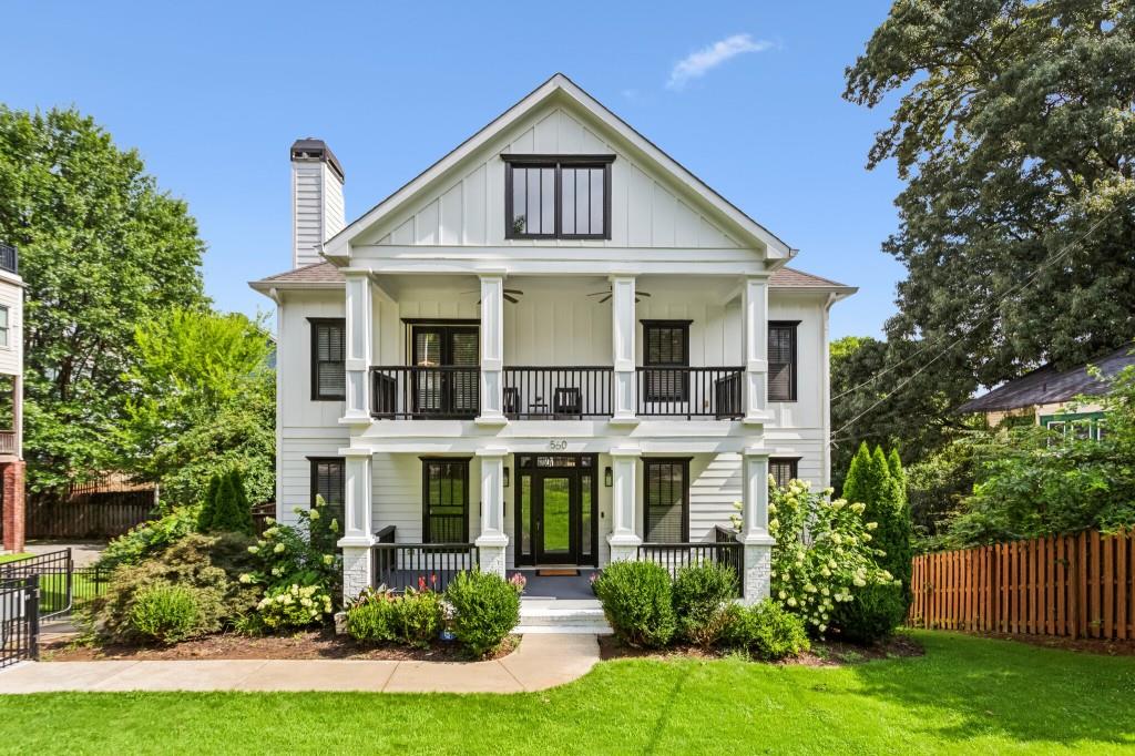 a view of white house with a big yard and large trees