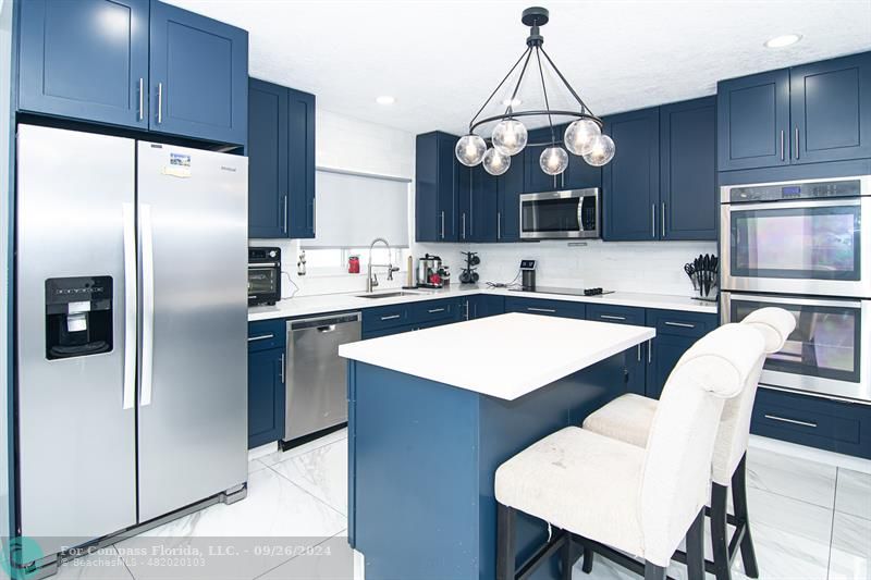 a kitchen with stainless steel appliances a table chairs and a refrigerator