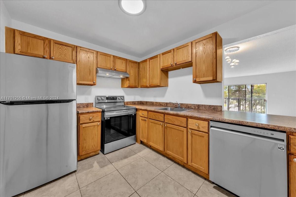 a kitchen with granite countertop a refrigerator stove top oven and sink