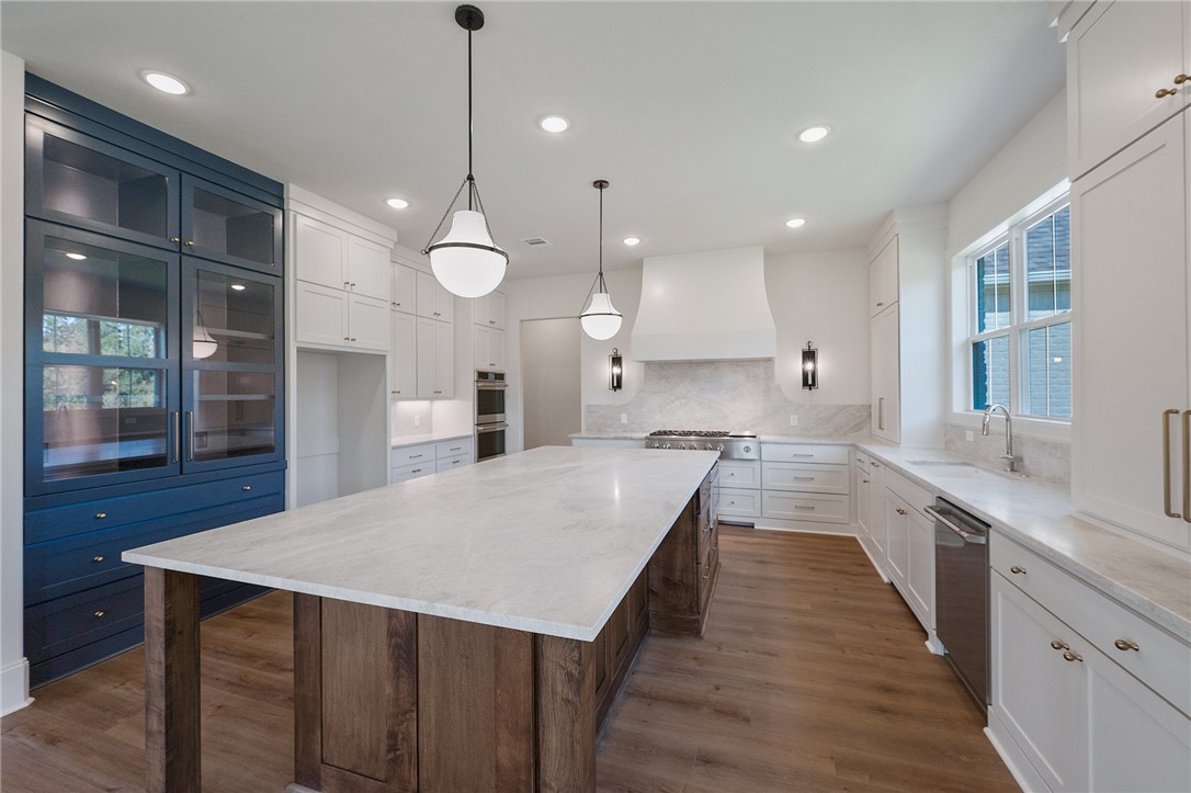 a large kitchen with kitchen island a stove a sink a center island and wooden floor