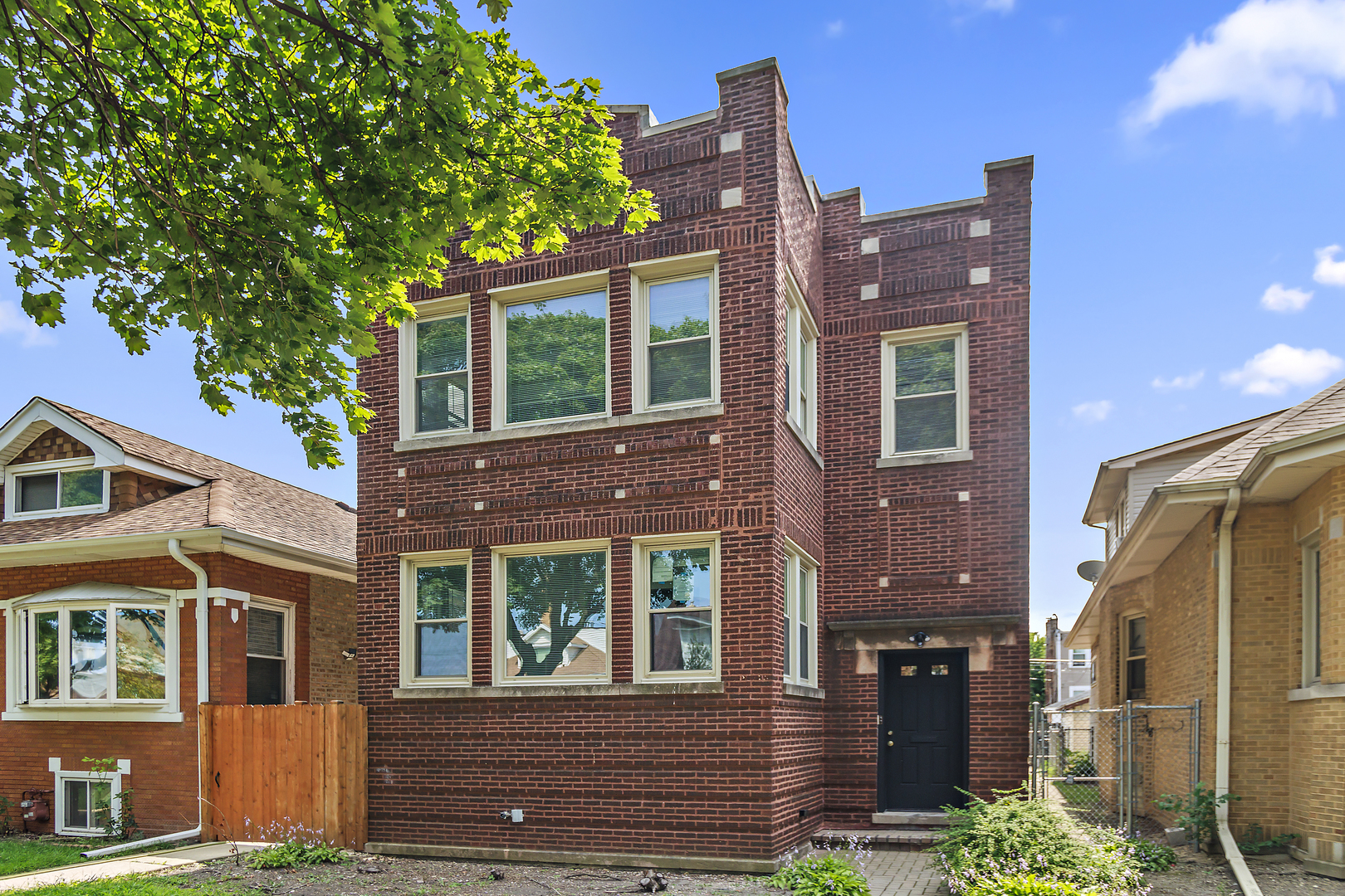 a view of a brick house with many windows and a tree