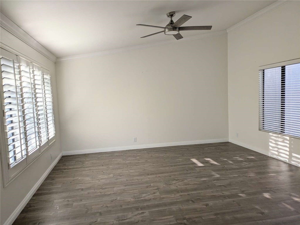 an empty room with wooden floor fan and windows