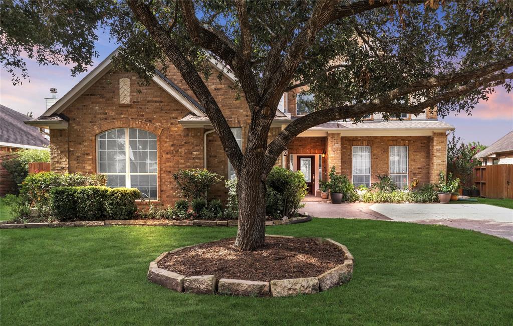 Two-story home with mature trees, featuring a large arched window and an inviting entryway