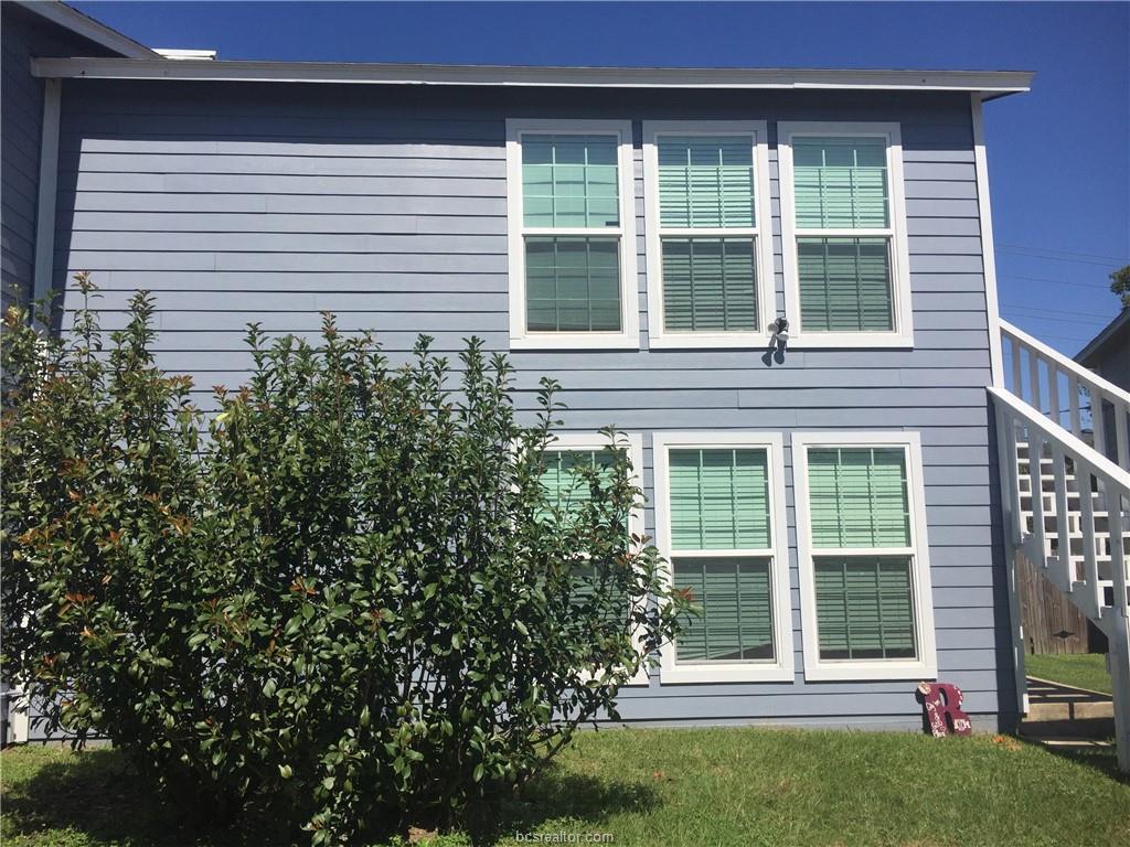 a view of a house that has a large window and plants