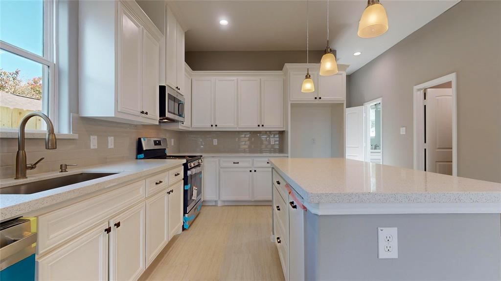 a kitchen with cabinets appliances a sink and a counter top space