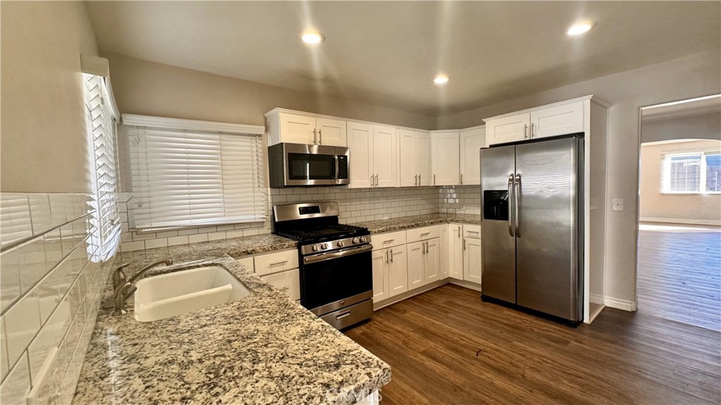 a kitchen with a refrigerator stove and wooden floor