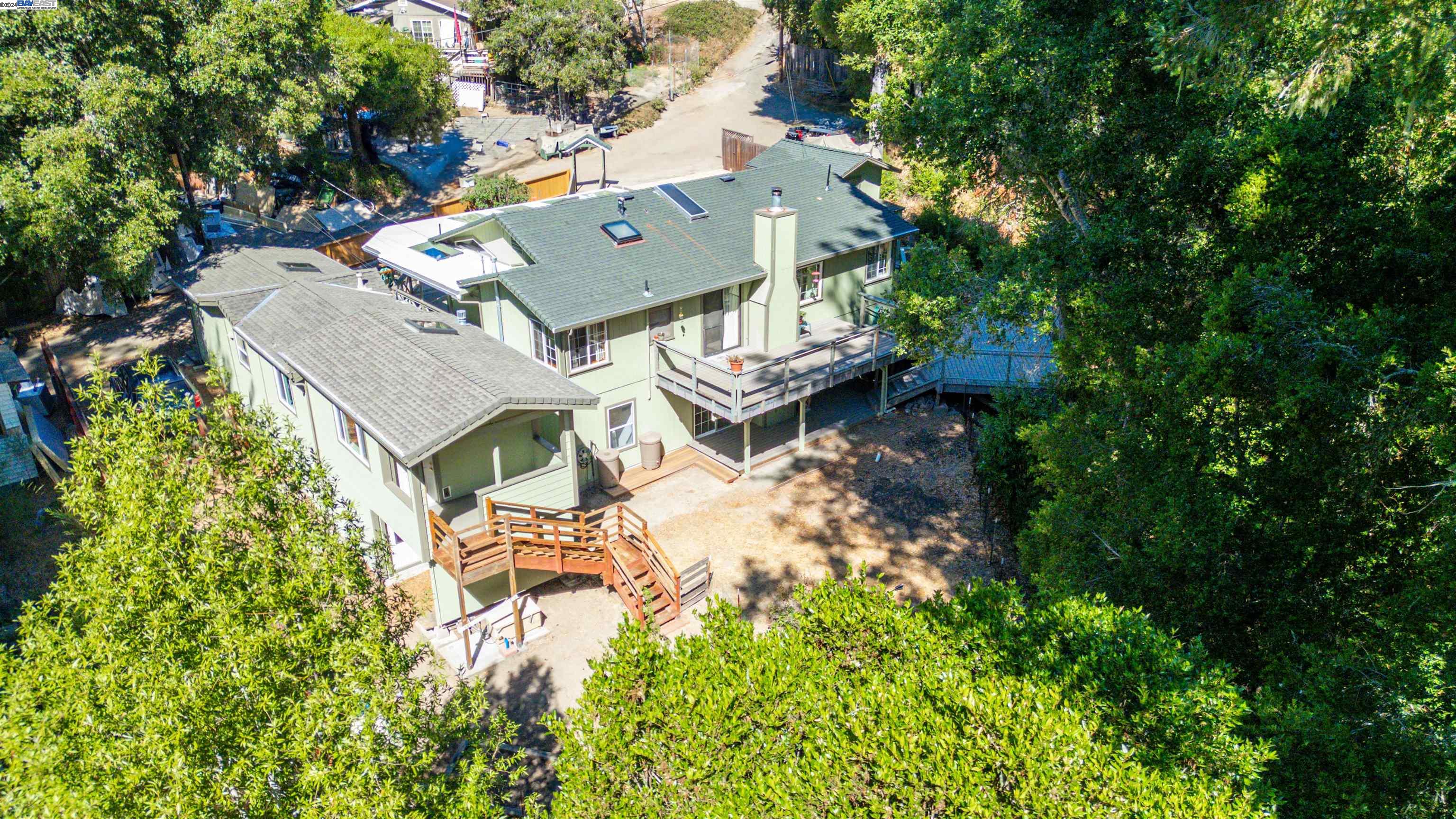 an aerial view of a house with garden space and trees all around