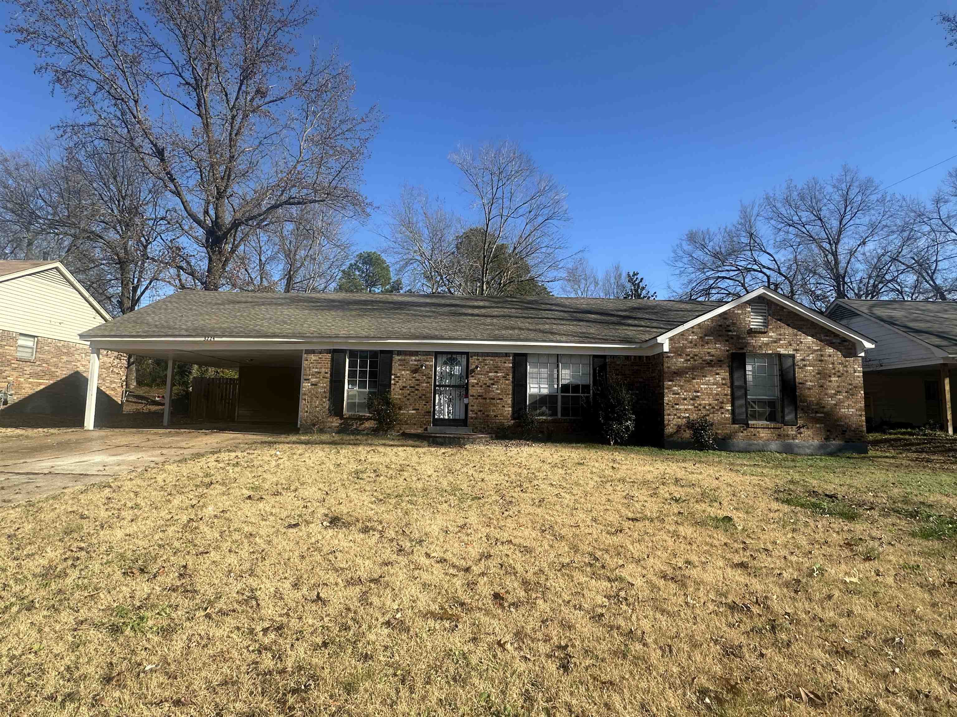 Ranch-style house with a front lawn and a carport