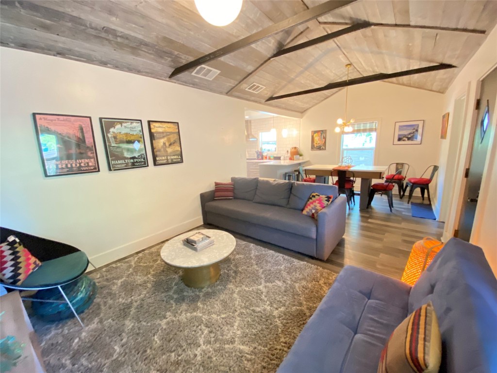 a living room with furniture and a dining table with wooden floor