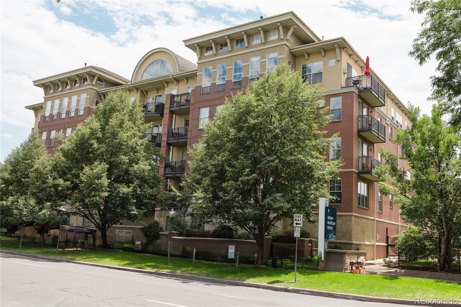 a front view of a residential apartment building with a yard and large trees