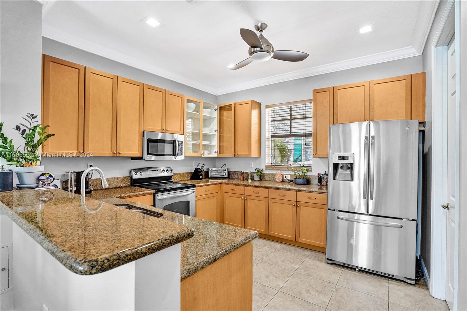 a kitchen with stainless steel appliances granite countertop refrigerator sink and large window