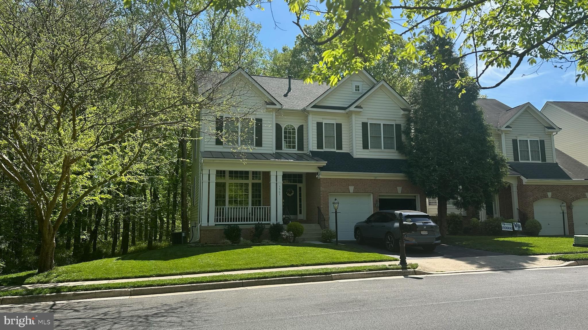 a view of a brick house with a yard plants and large trees