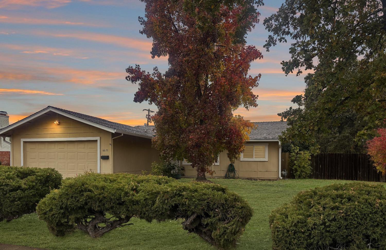 a view of a house with a yard and large trees