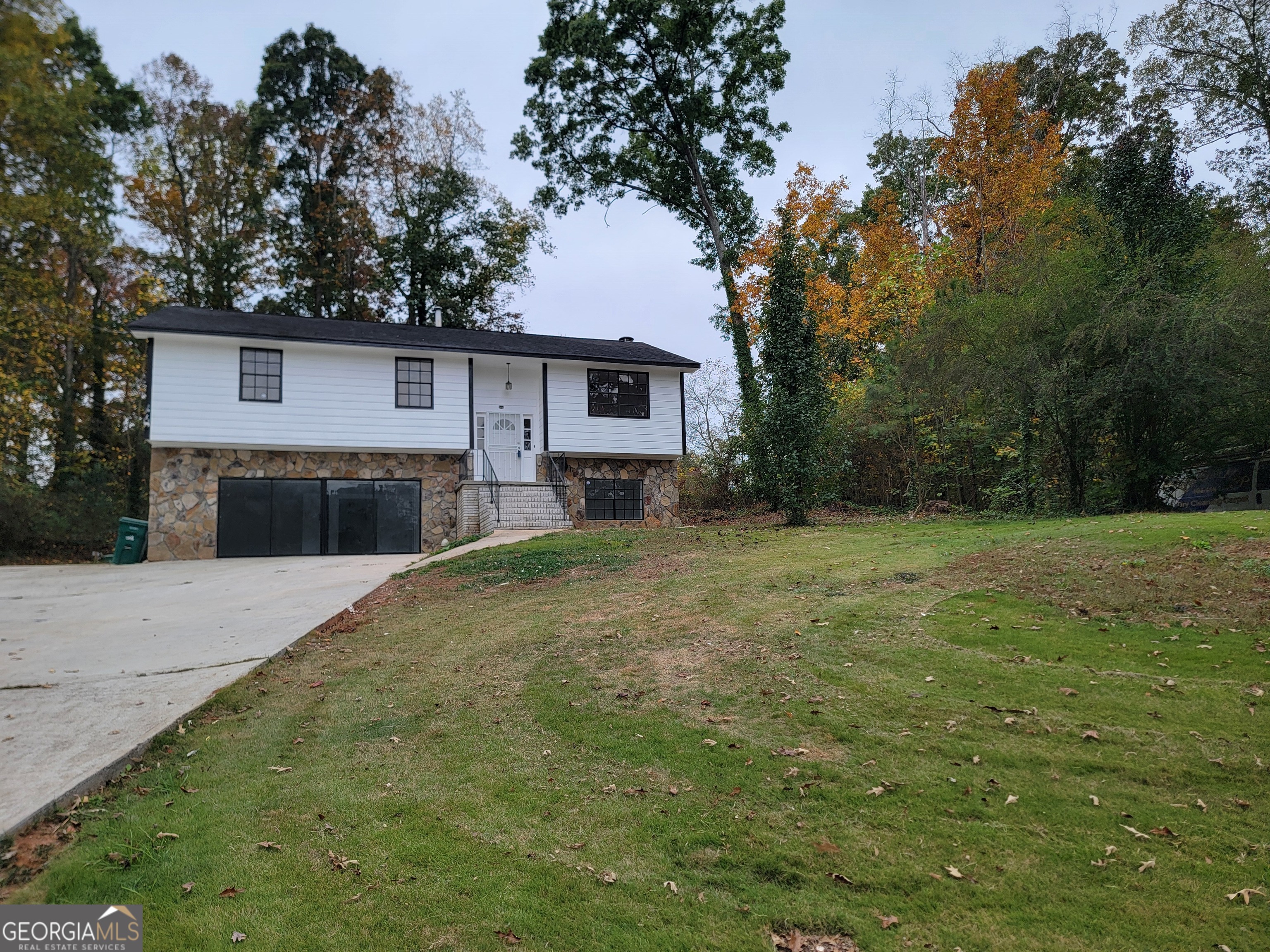 a front view of house with yard and trees in the background