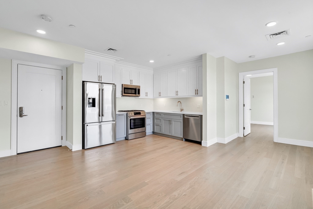 a kitchen with stainless steel appliances a refrigerator and white cabinets