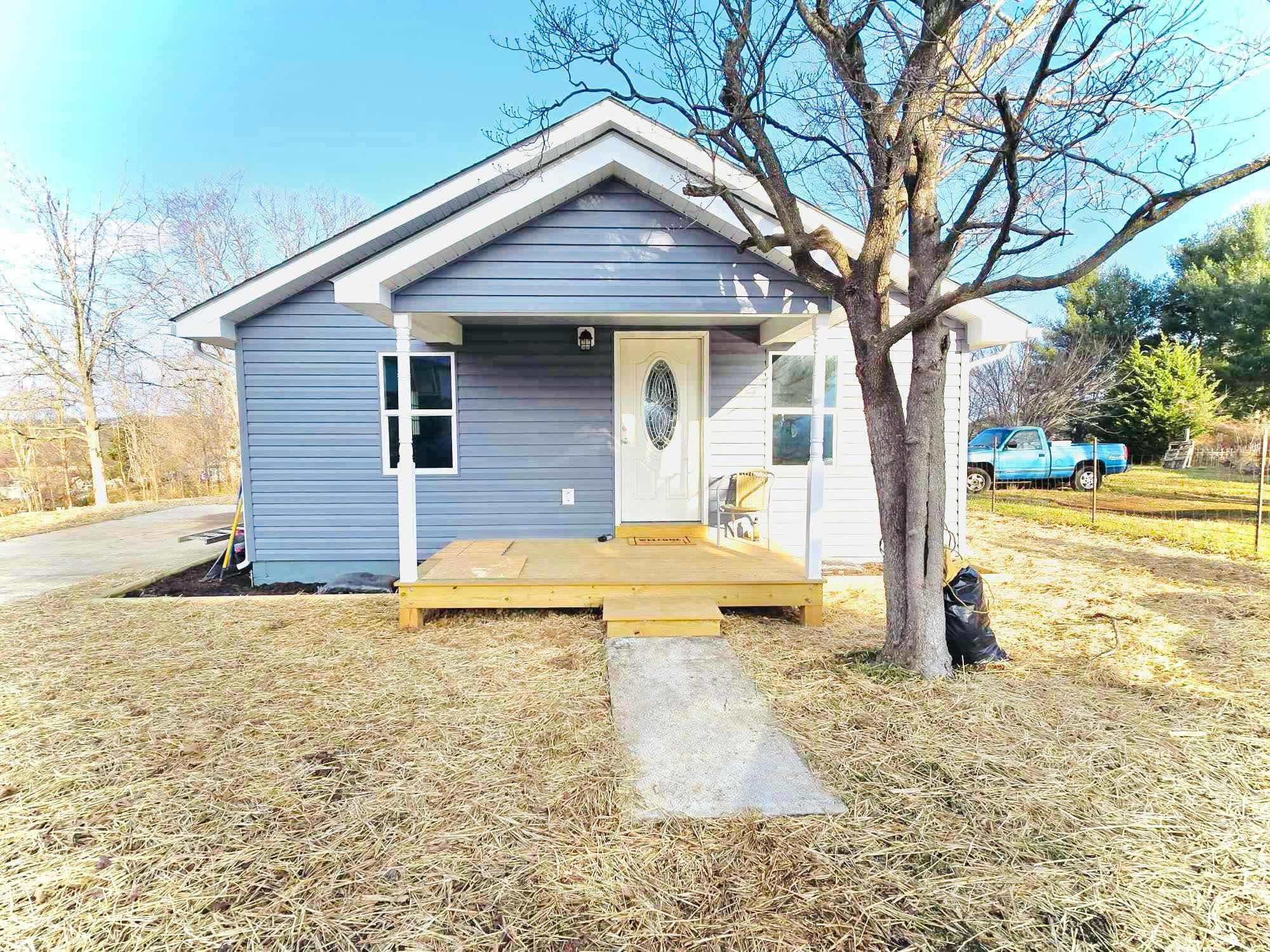 a view of a house with a yard and large tree