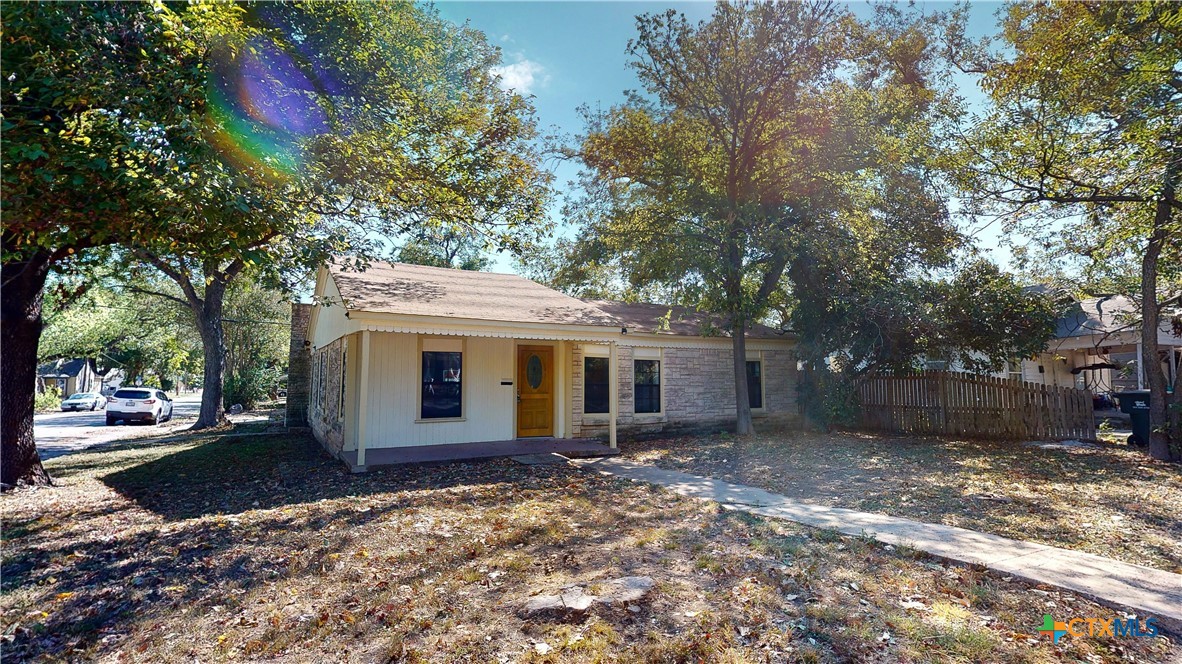 a view of a house with a yard and large tree