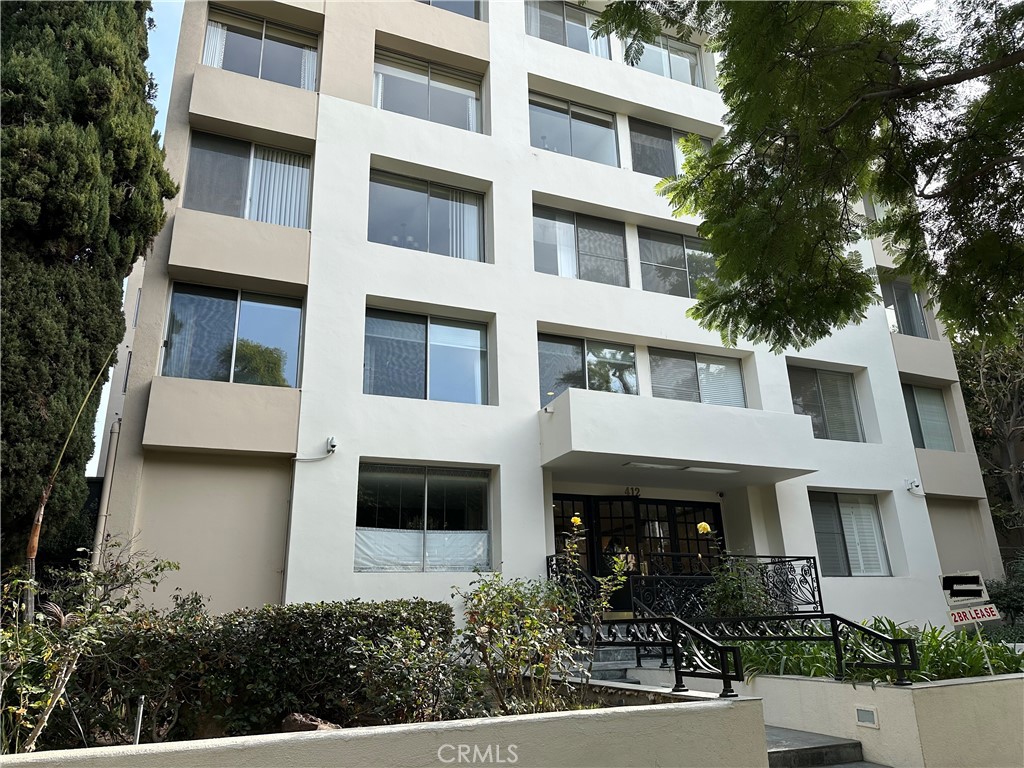 a front view of a multi story building with plants