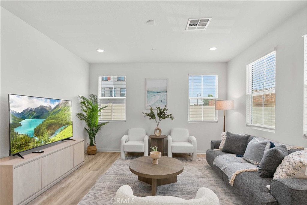 a living room with furniture a flat screen tv and a large window