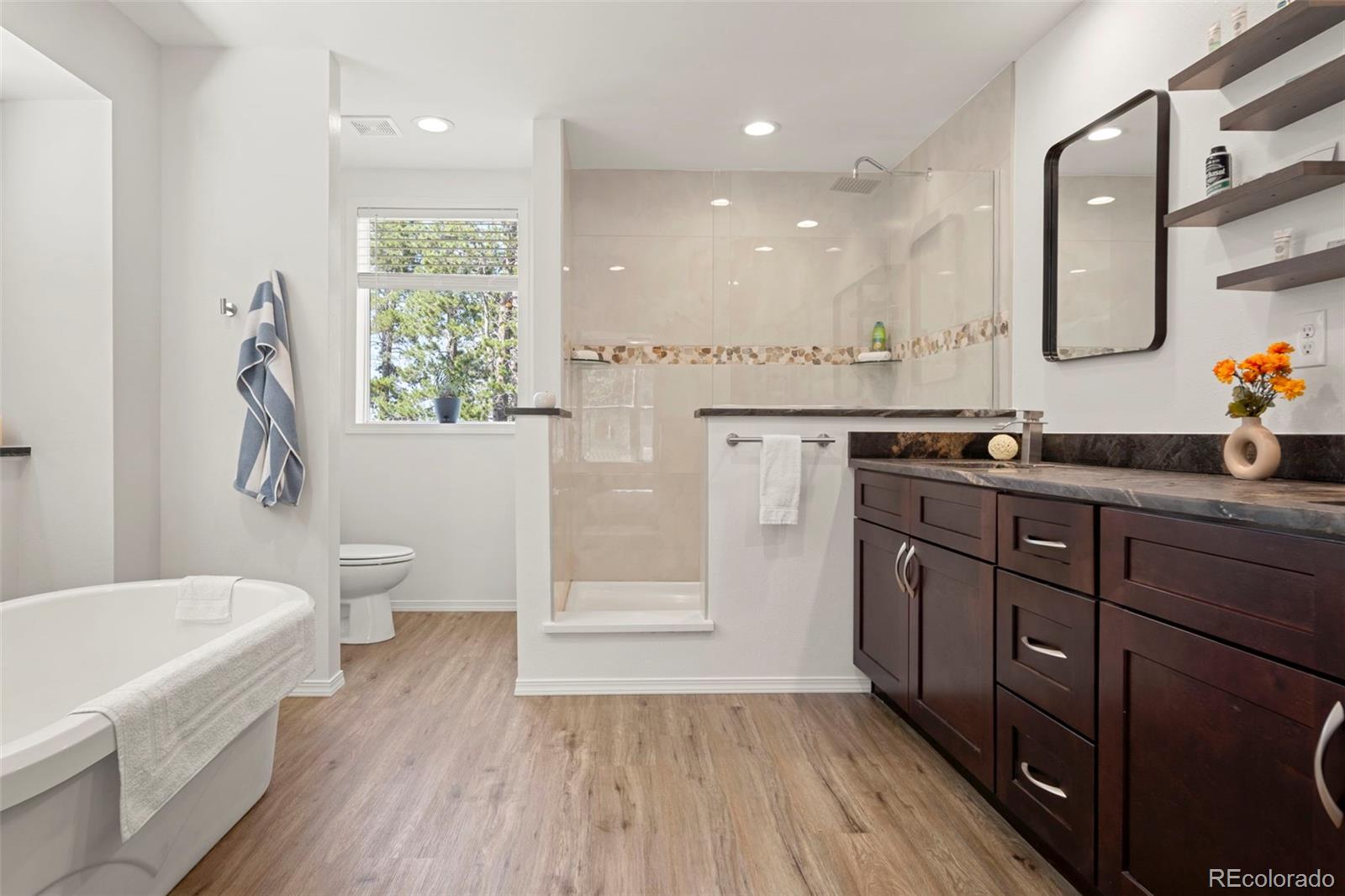 a spacious bathroom with a granite countertop sink a toilet a mirror and bathtub