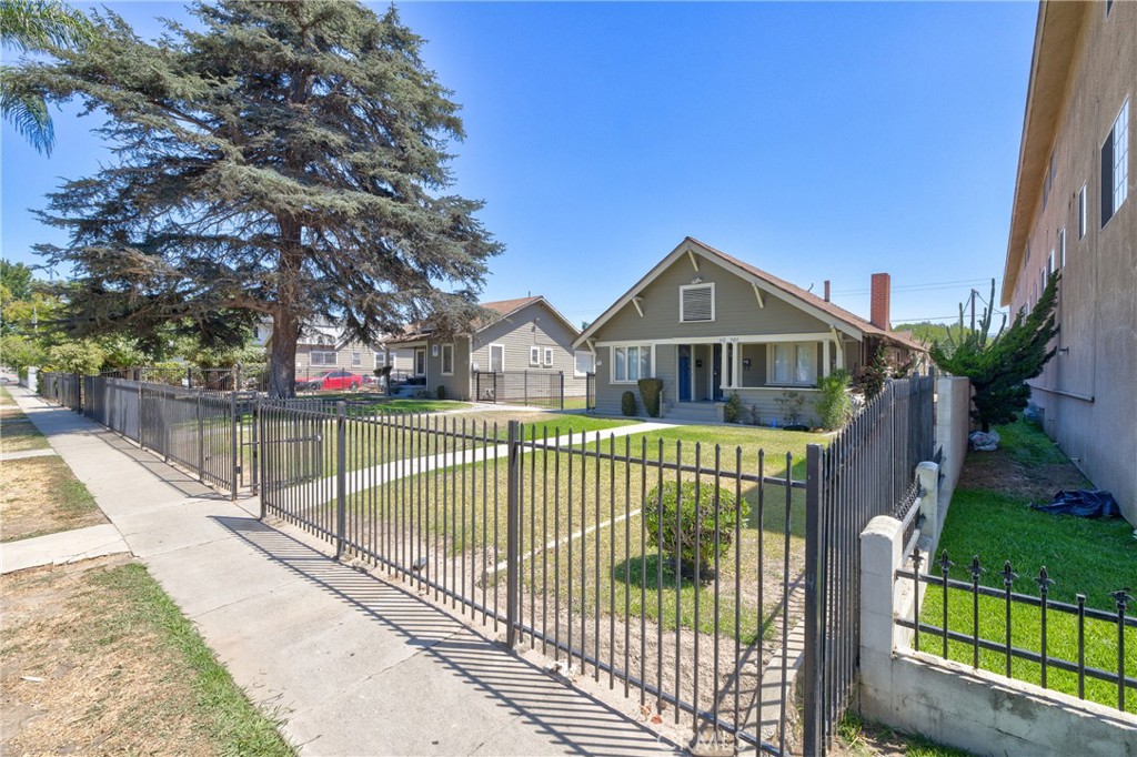 a view of house with a yard and iron fence