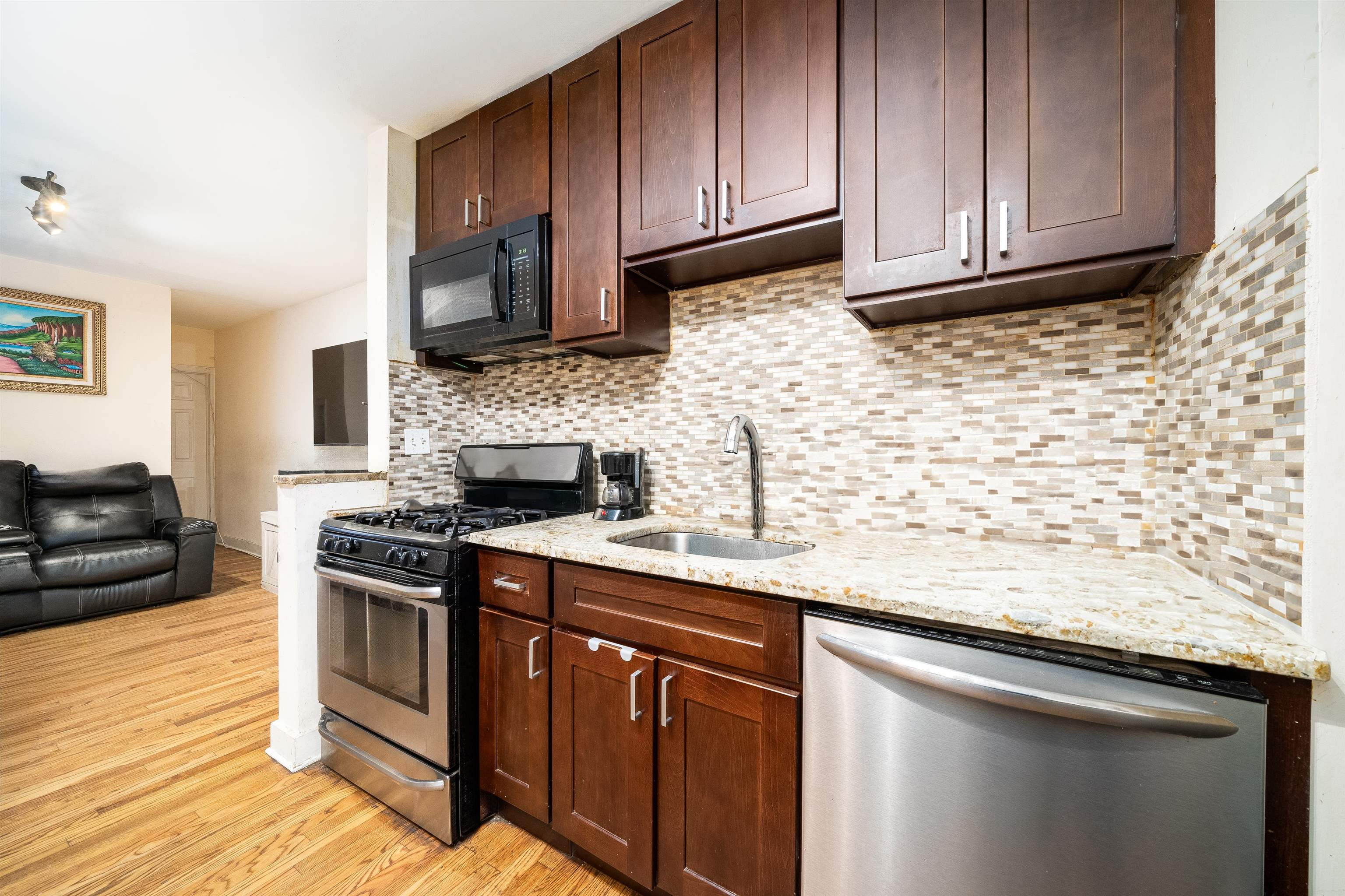 a kitchen with granite countertop wood cabinets stainless steel appliances and a wooden floor