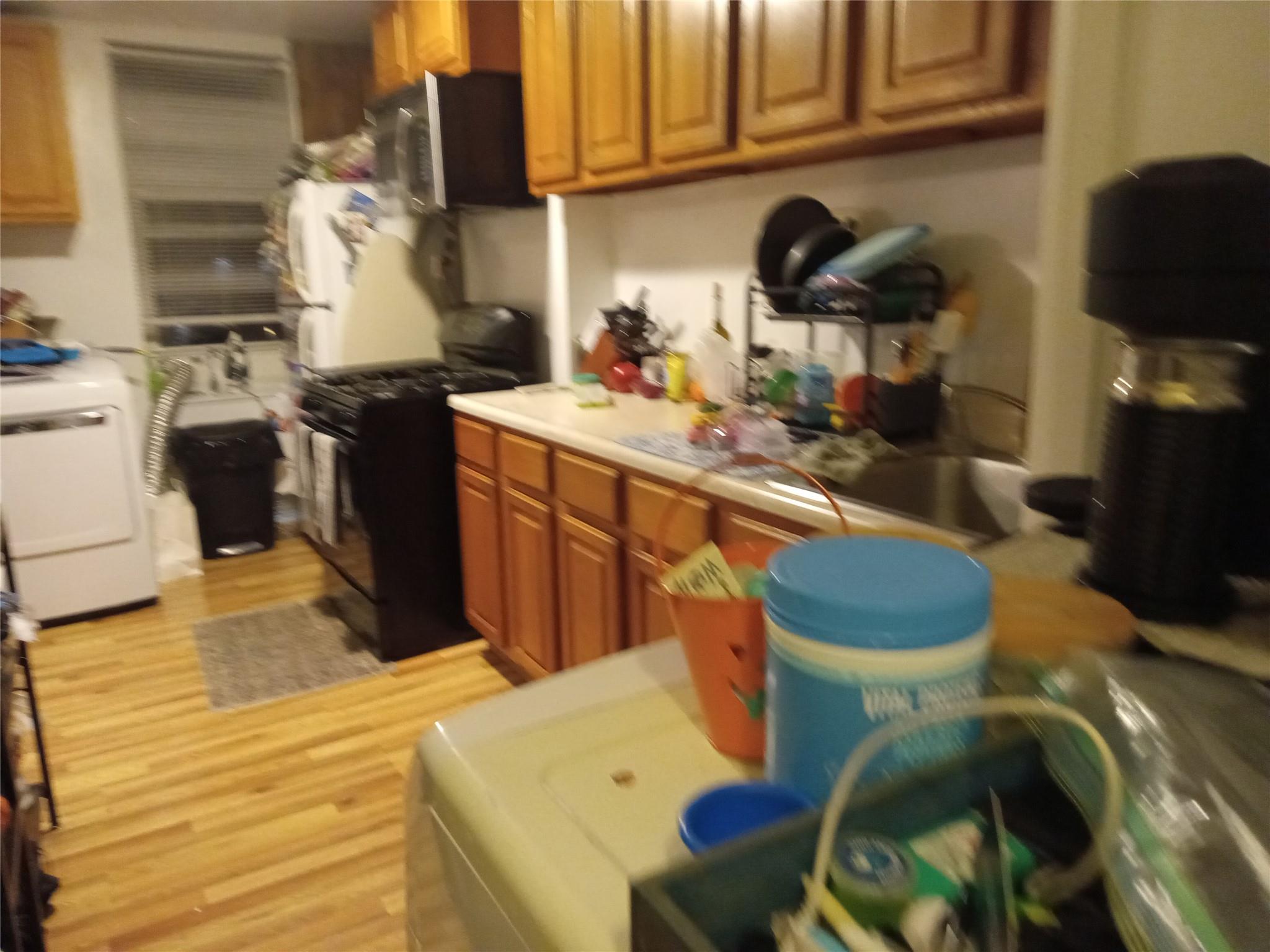 Kitchen featuring washer and dryer, light hardwood / wood-style floors, and black range