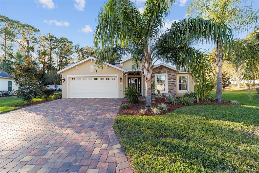 a front view of a house with a garden and palm trees