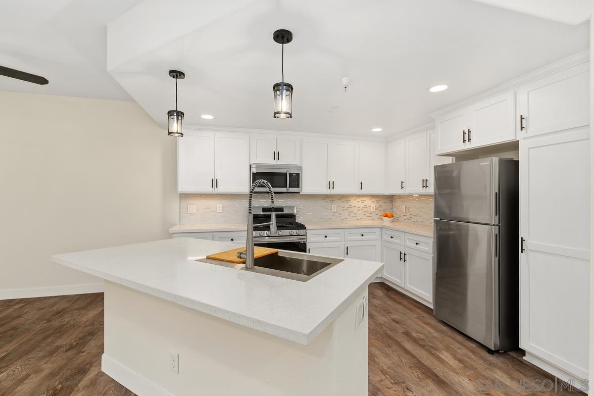 a kitchen with a refrigerator a stove and white cabinets with wooden floor