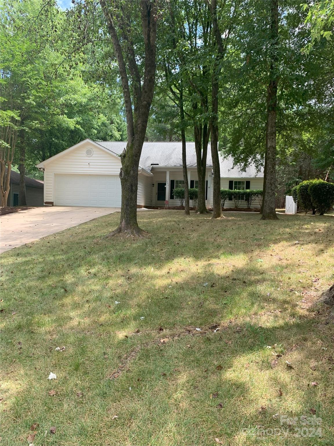 a view of a house with a yard and large trees