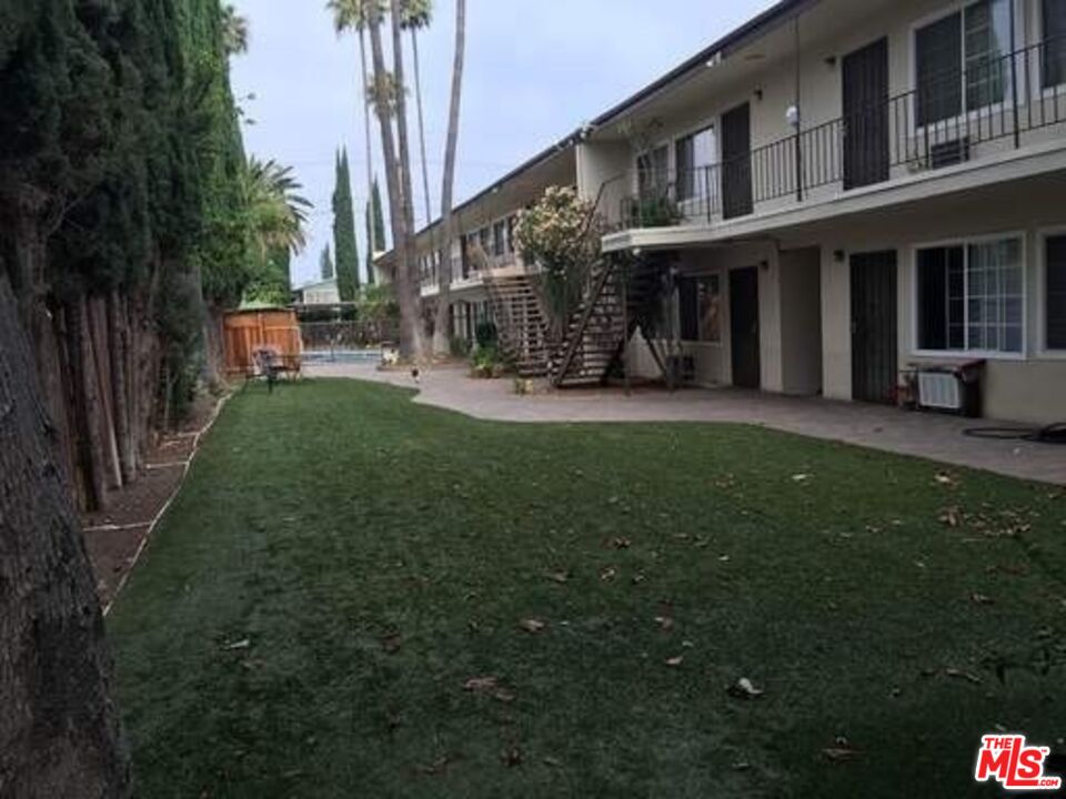 a view of a brick house with a big yard and large trees