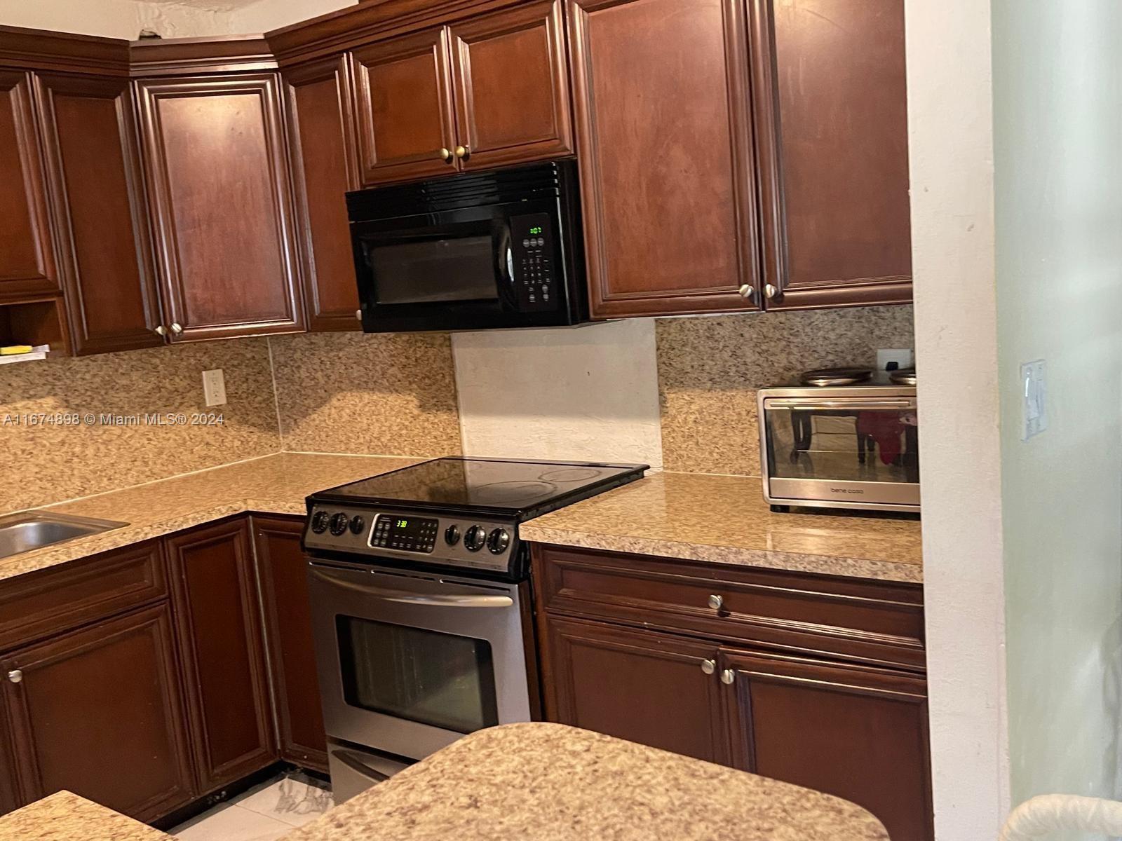 a kitchen with granite countertop a stove and a microwave