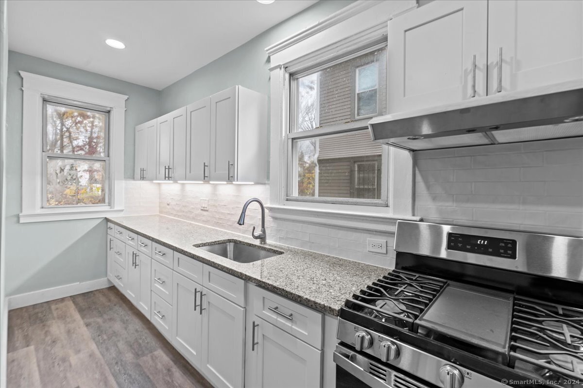 a kitchen with stainless steel appliances granite countertop a sink stove and cabinets