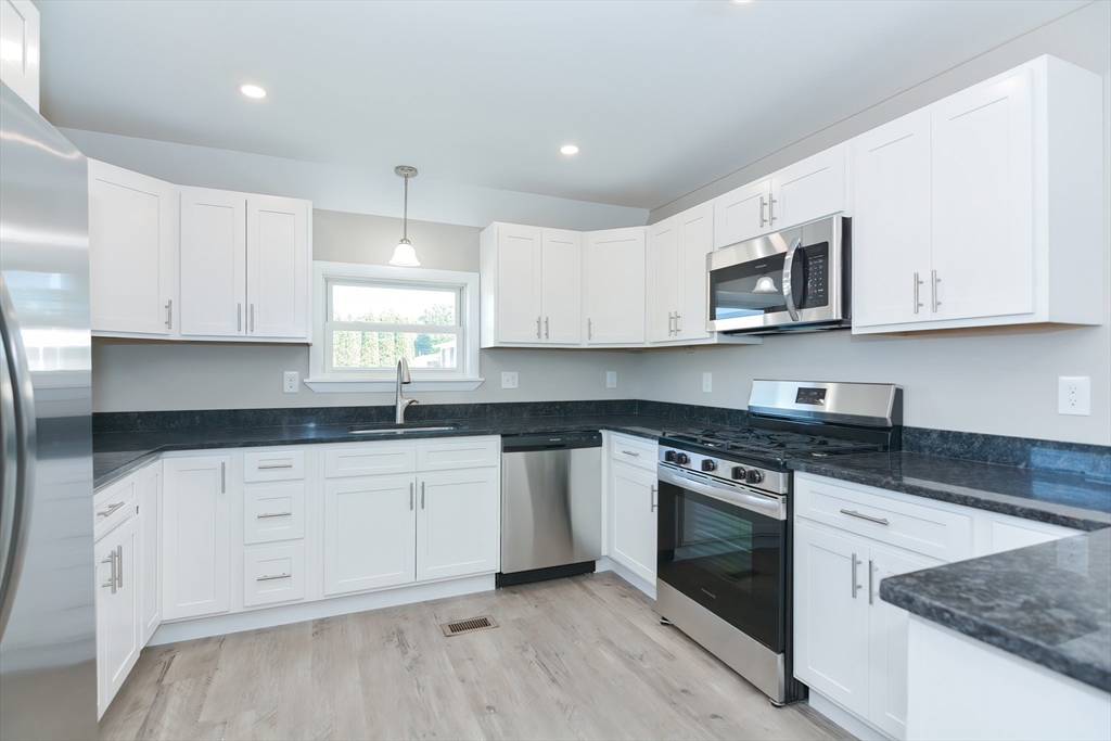 a kitchen with granite countertop white cabinets white stainless steel appliances and a sink