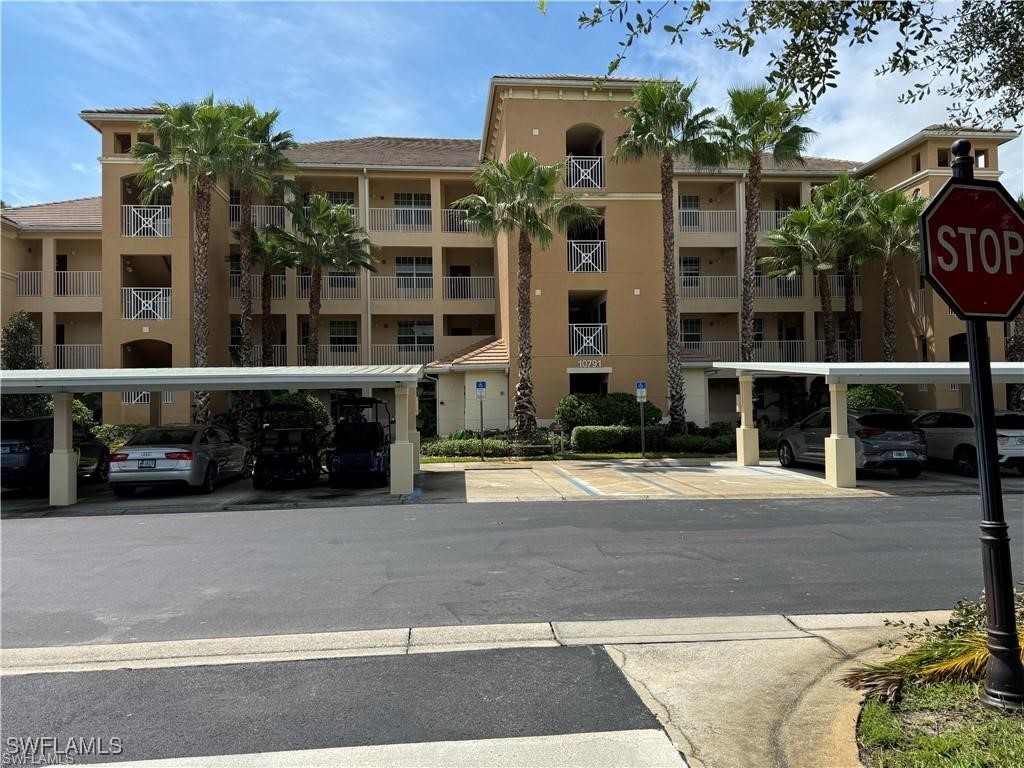 a front view of a building with a garden and parking space