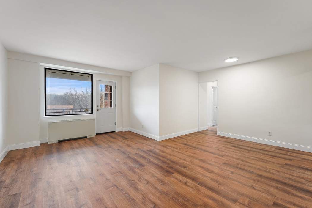 a view of an empty room with wooden floor and a window