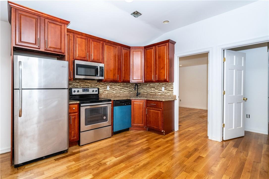 Kitchen featuring light wood flooring, tasteful backsplash, sink, granite counters tops, and stainless steel appliances