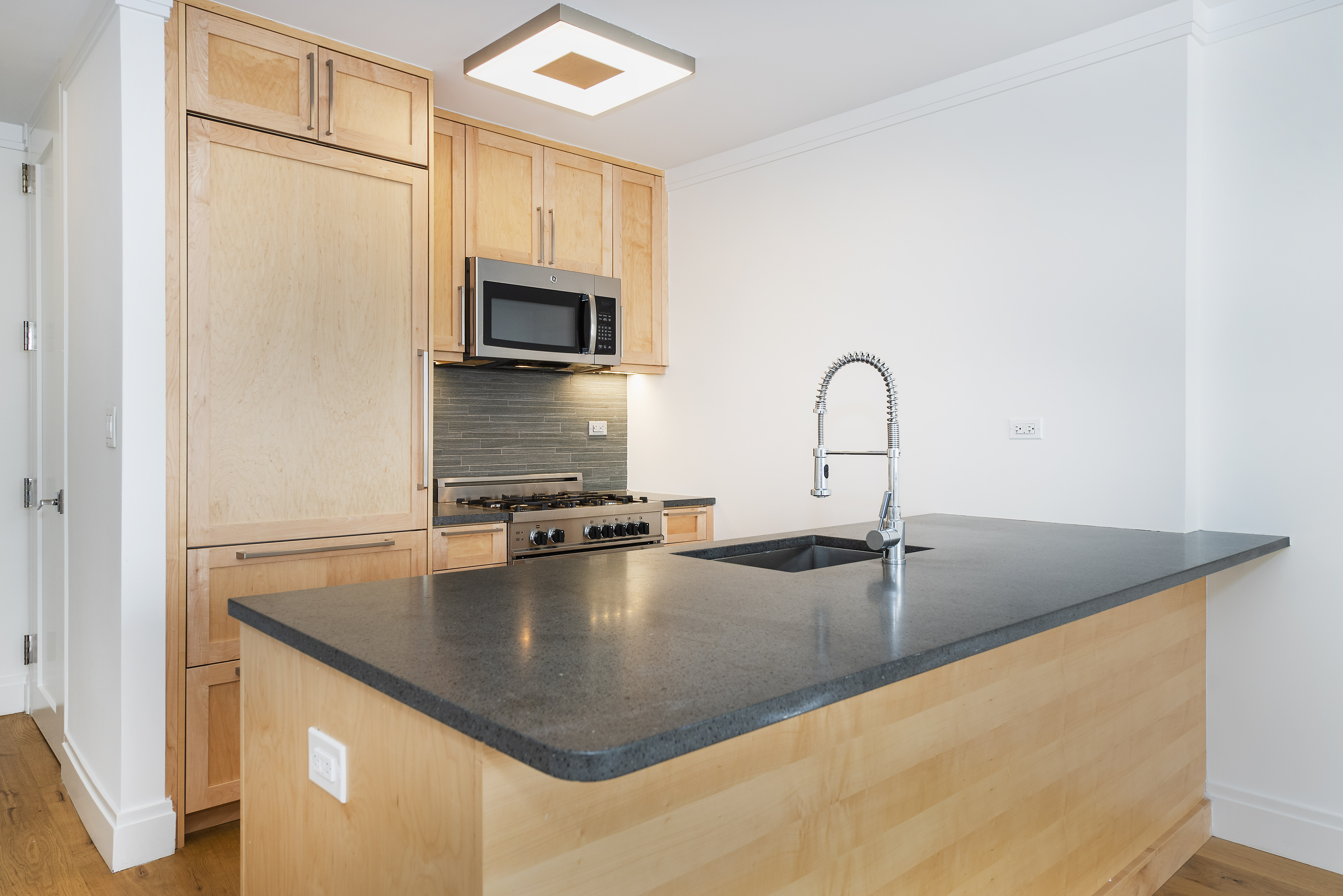 a kitchen with sink a refrigerator and microwave