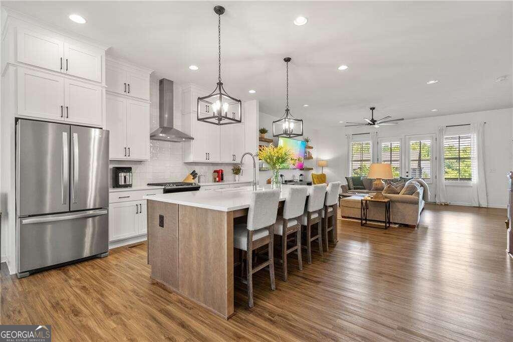 a kitchen with stainless steel appliances granite countertop a refrigerator a stove a sink dishwasher a dining table and chairs with wooden floor