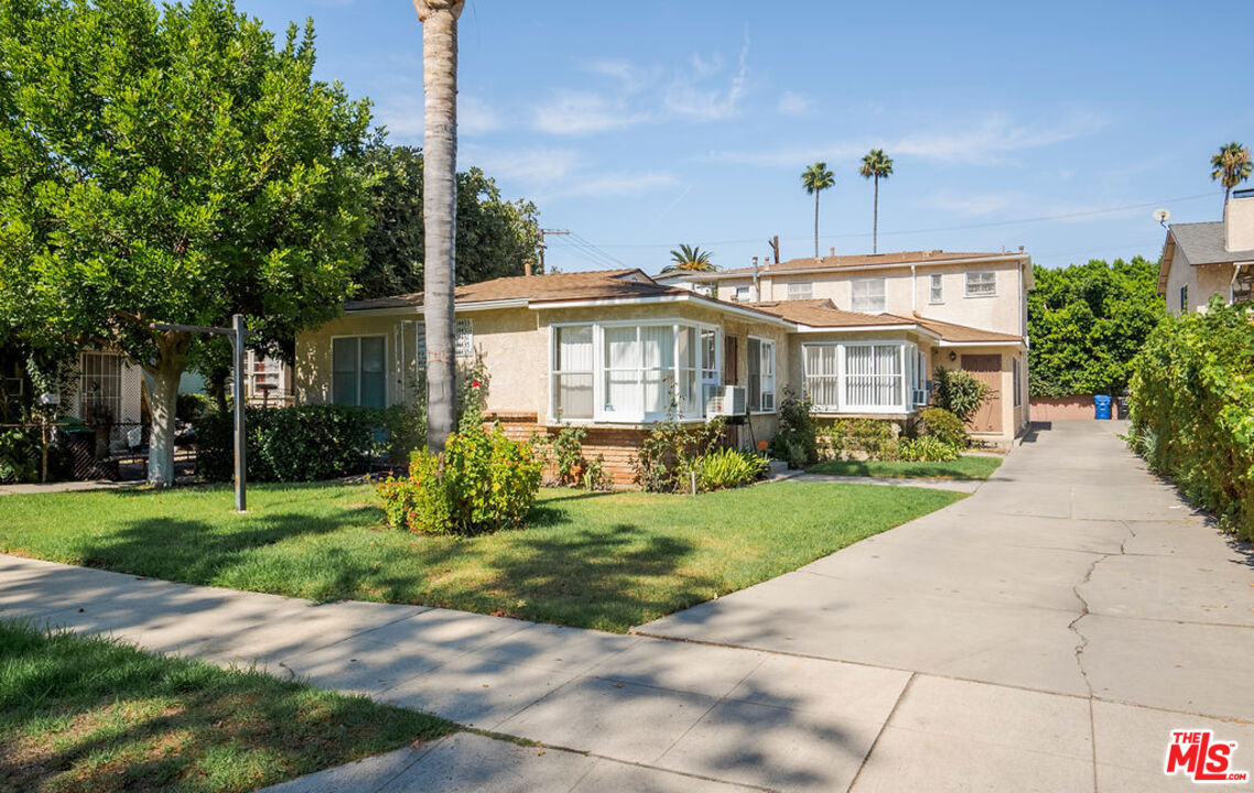 a front view of a house with a yard and potted plants