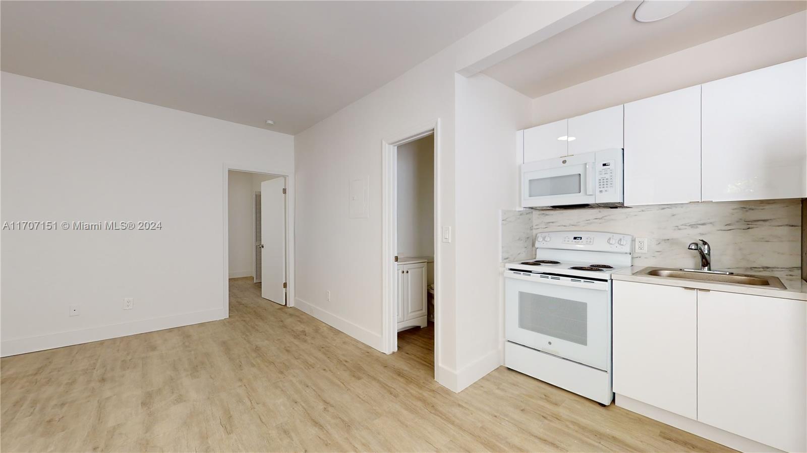 a kitchen with granite countertop white cabinets and white appliances