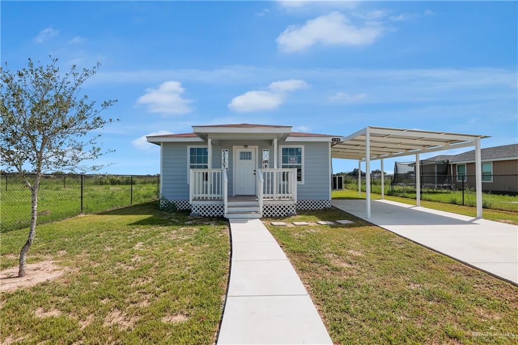 View of front of property with a front lawn, a carport, and covered porch