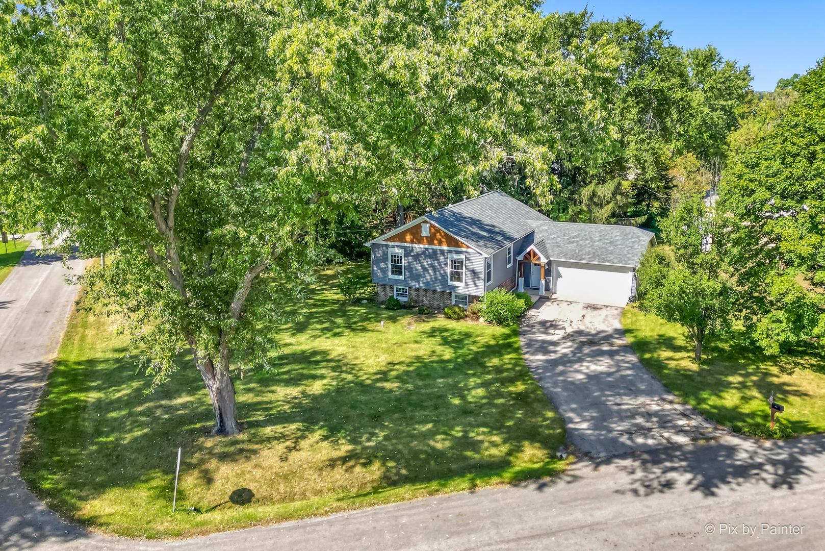 a view of a house with a yard and large trees