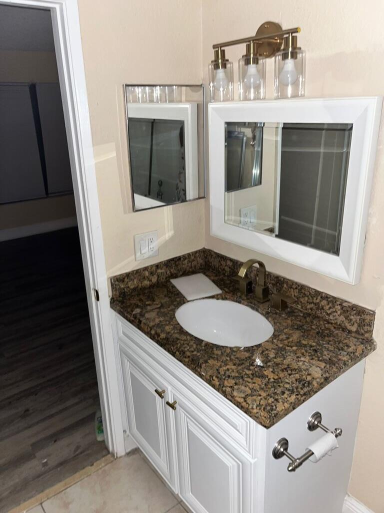 a bathroom with a granite countertop sink and a mirror