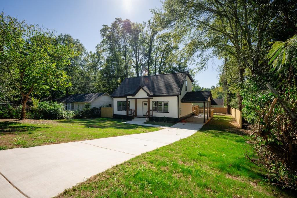 a front view of a house with a yard and large trees