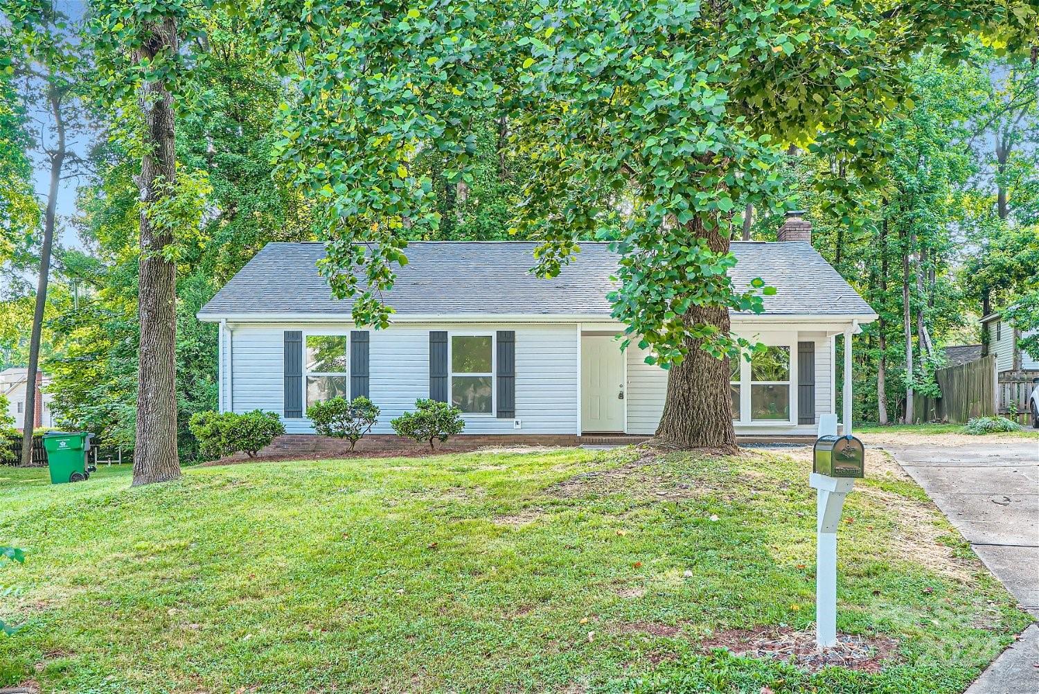 a front view of a house with a yard and trees